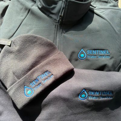 Custom embroidered workwear for Sentinel Water Services including softshell jacket, beanie hat and sweatshirt with blue embroidered company logo by KMVT Workwear